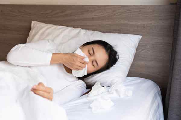 Eine Frau im Bett mit Hausstaub-allergie